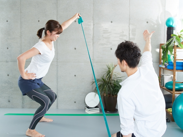 トレーナーと一緒にトレーニングを行う女性