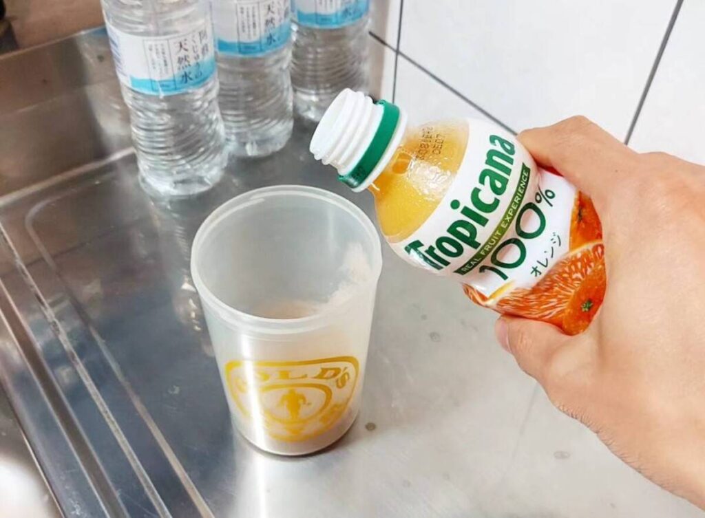 プロテインシェイカーにオレンジジュースを注ぐ