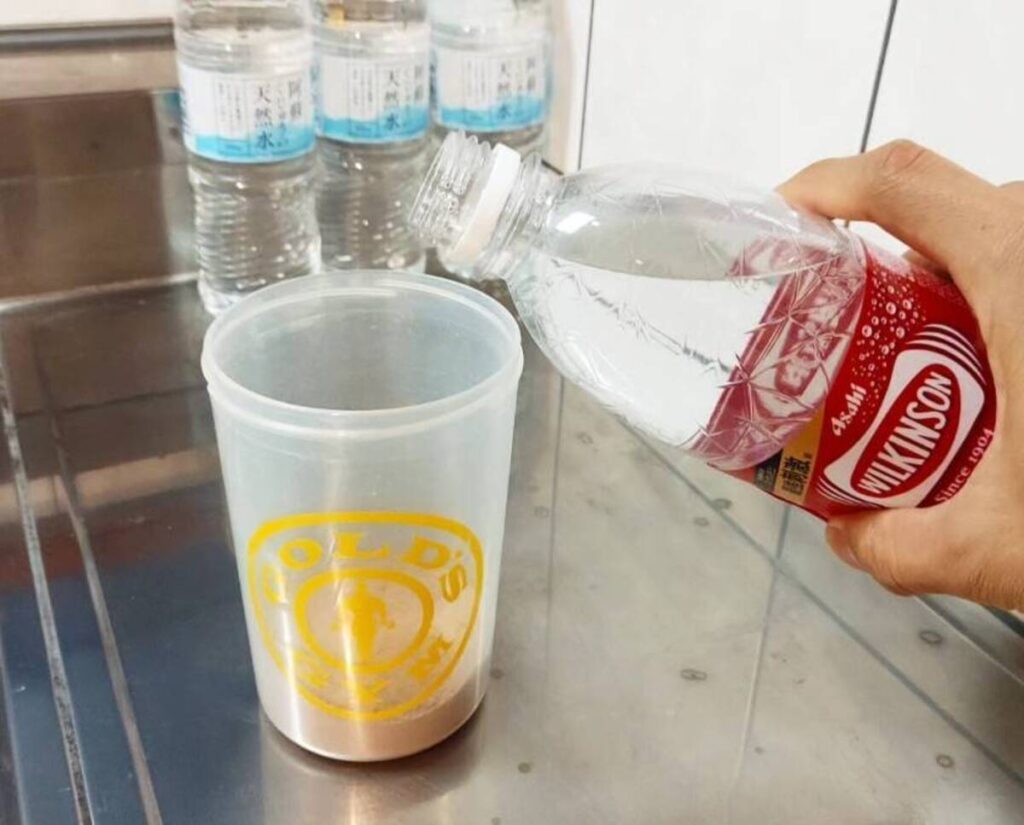 プロテインシェイカーに炭酸水を注ぐ様子