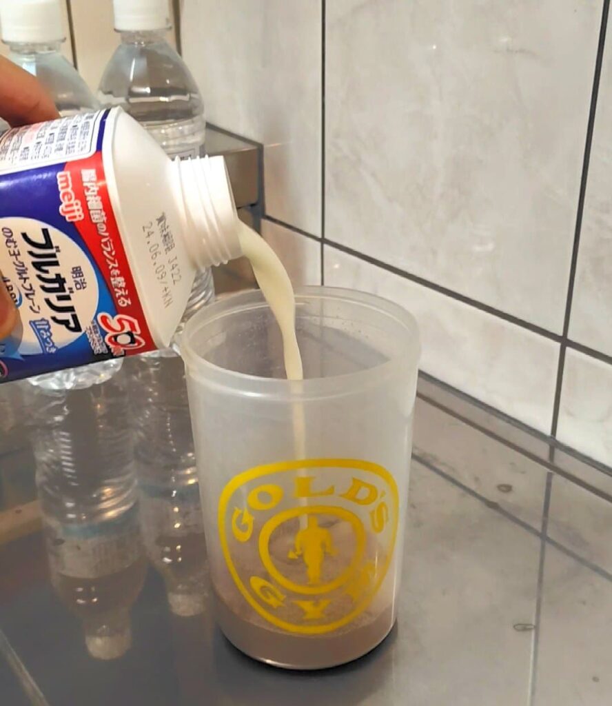 プロテインシェイカーに飲むヨーグルトを注ぐ様子