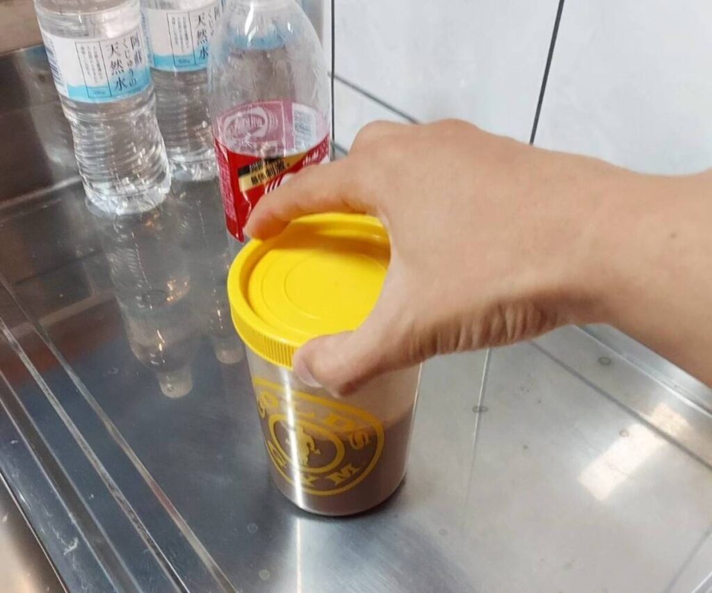 プロテインシェイカーの蓋を開ける様子